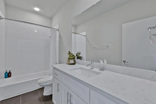 a bathroom with a granite countertop sink a toilet and shower