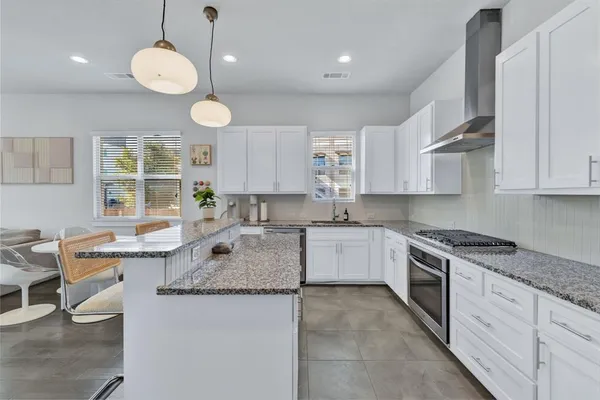 a kitchen with stainless steel appliances granite countertop a sink a stove and a wooden floors