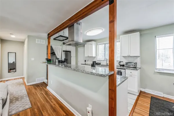 a kitchen with stainless steel appliances granite countertop a refrigerator a stove and a sink with wooden floor