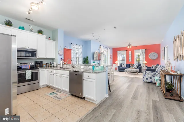 a kitchen with stainless steel appliances a stove a sink dishwasher a oven with white cabinets and wooden floor