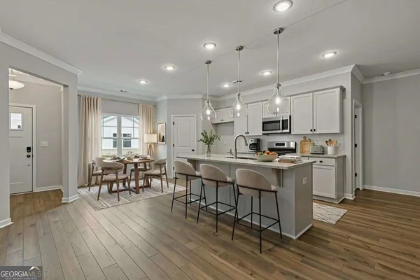 a kitchen with stainless steel appliances a dining table chairs stove refrigerator and cabinets