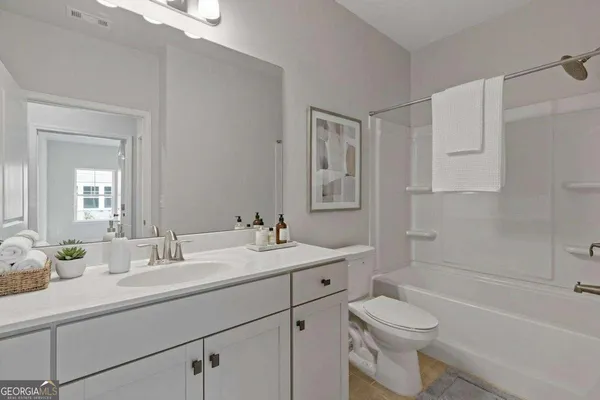 a bathroom with a toilet a sink a mirror a bathtub and vanity