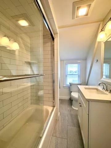 a bathroom with a granite countertop sink a toilet and shower