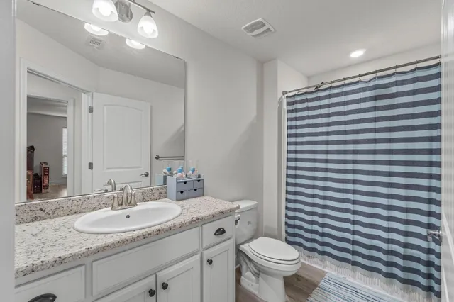 a bathroom with a granite countertop toilet a sink and a mirror