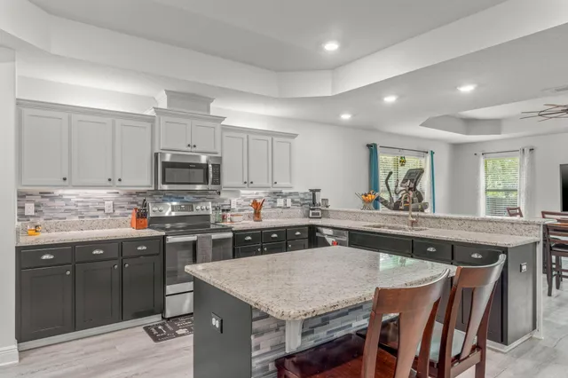 a kitchen with stainless steel appliances granite countertop a table chairs sink refrigerator and cabinets