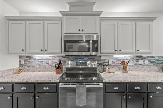 a kitchen with granite countertop a stove sink and cabinets