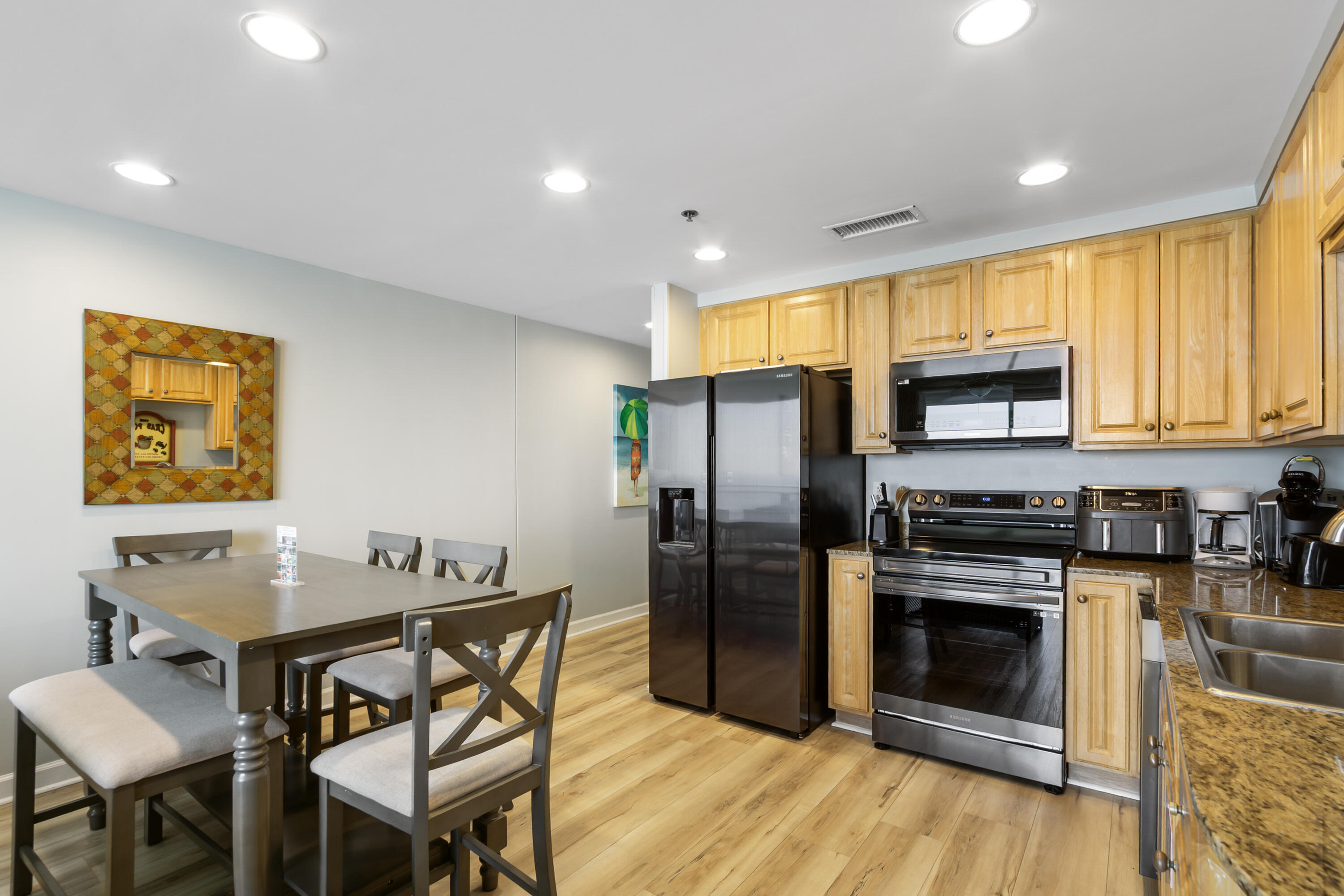 17739 Front Beach Road, Unit 1902W Panama City Beach, FL 32413 - Photo 15 of 54 a kitchen with stainless steel appliances granite countertop a stove a refrigerator a sink a dining table and chairs with wooden floor