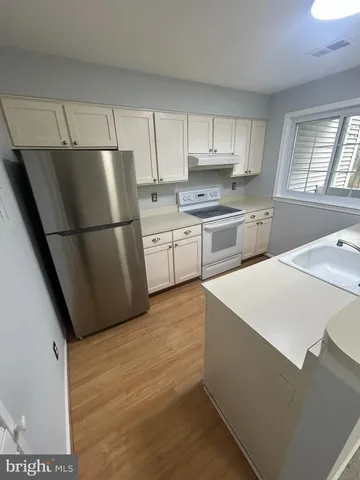 a kitchen with stainless steel appliances white cabinets and a refrigerator