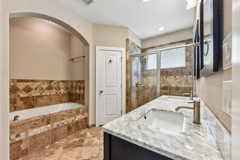 a large bathroom with a granite countertop tub sink and mirror