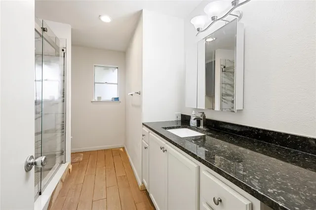 a bathroom with a granite countertop sink a mirror and shower