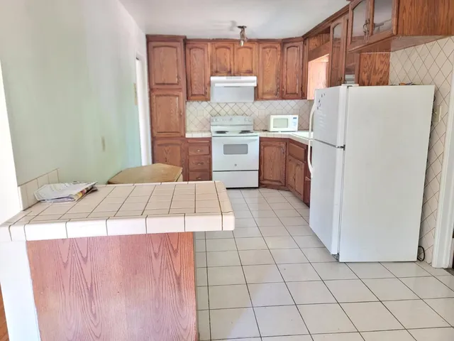 a kitchen with a refrigerator a stove top oven and cabinets