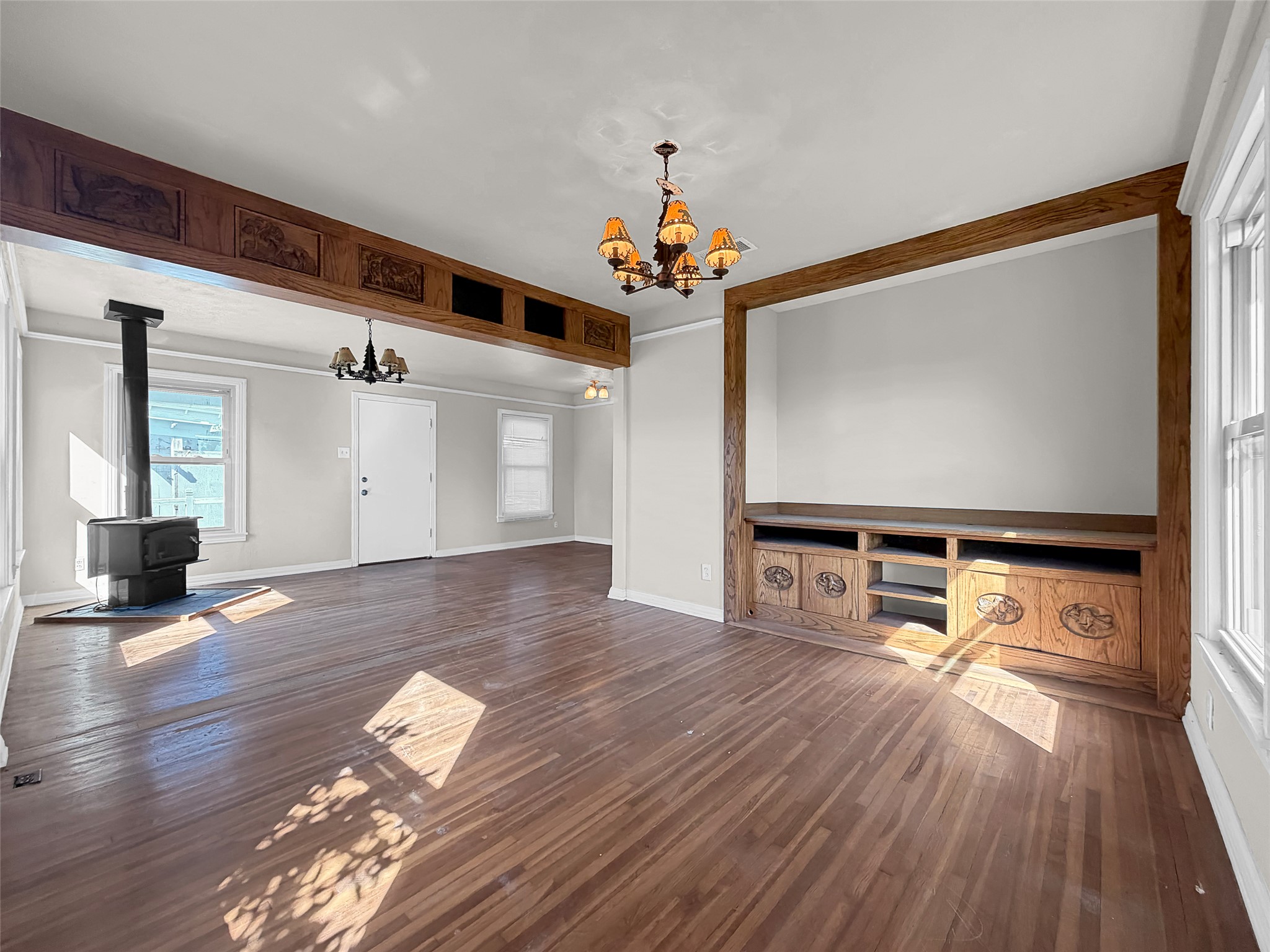 925 Long Hollow Road Dale, TX 78616 - Photo 16 of 26 Expansive living area featuring wood-finish flooring, a freestanding wood-burning stove, and a built-in media console with decorative cabinetry