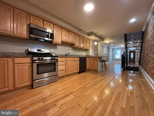 a large kitchen with stainless steel appliances granite countertop a stove and a wooden floors