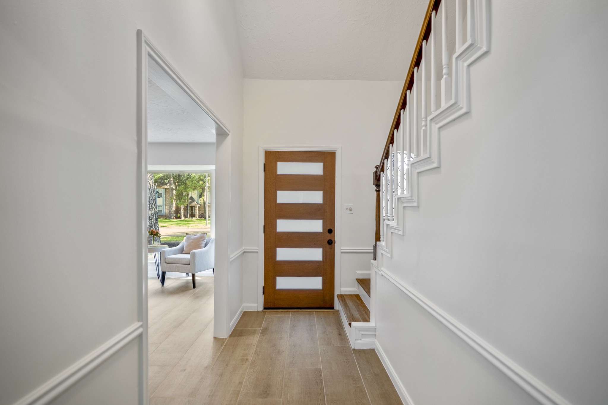 6303 Larkmount Drive Spring, TX 77389 - Photo 5 of 50 Turning back toward the entry, the brand new 5-panel front door makes a stylish first impression framed by fresh paint, new wood-look tile flooring, and the warm oak staircase nearby. Just off to the left, the formal living room opens from the foyer, beginning the natural flow through the home’s connected downstairs spaces.