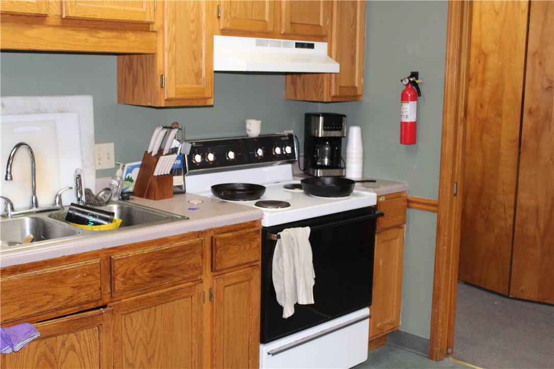158 Ragon Road Tilly, AR 72679 - Photo 11 of 51 Kitchen featuring wood-finish cabinetry, a double basin stainless steel sink, and a white oven range with an overhead vent hood
