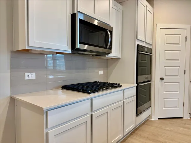 a view of a kitchen with microwave and refrigerator