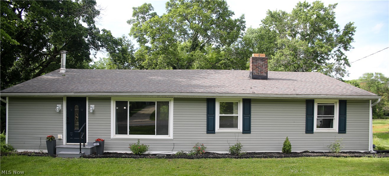 Ranch-style exterior with gray horizontal siding, dark teal shutters, and a charcoal shingle roof