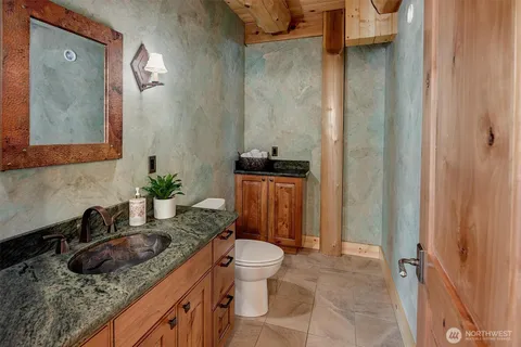 a bathroom with a granite countertop sink a toilet a mirror and shower curtain