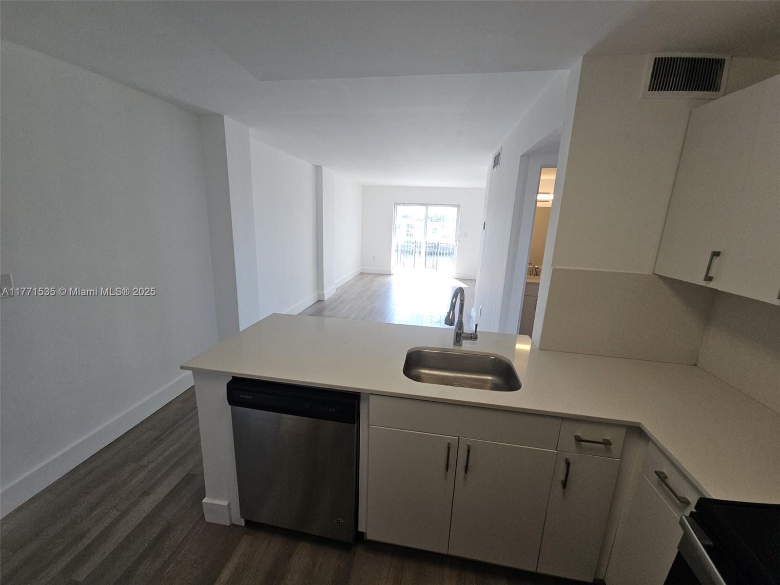 a kitchen with a sink and wooden floor