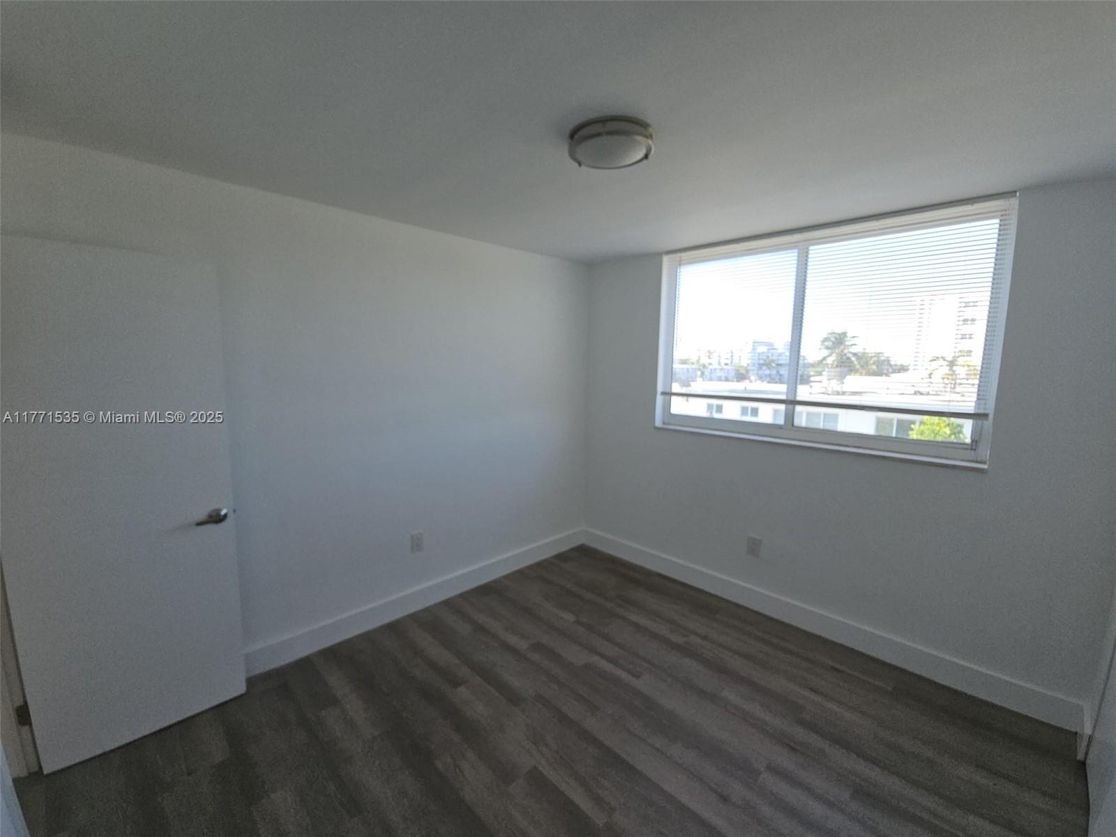 8101 Crespi Boulevard, Unit 304 Miami Beach, FL 33141 - Photo 12 of 25 a view of an empty room with wooden floor and windows