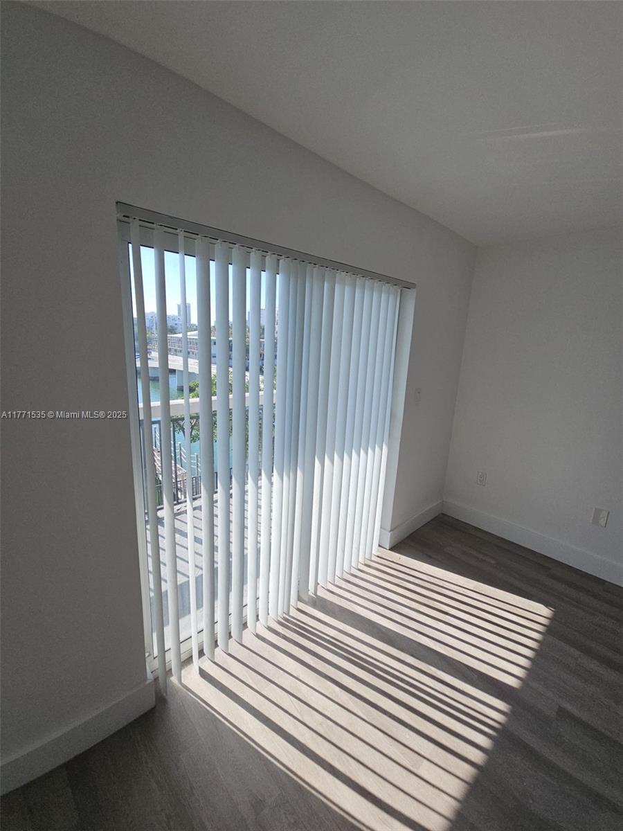 8101 Crespi Boulevard, Unit 304 Miami Beach, FL 33141 - Photo 6 of 25 an empty room with wooden floor and windows