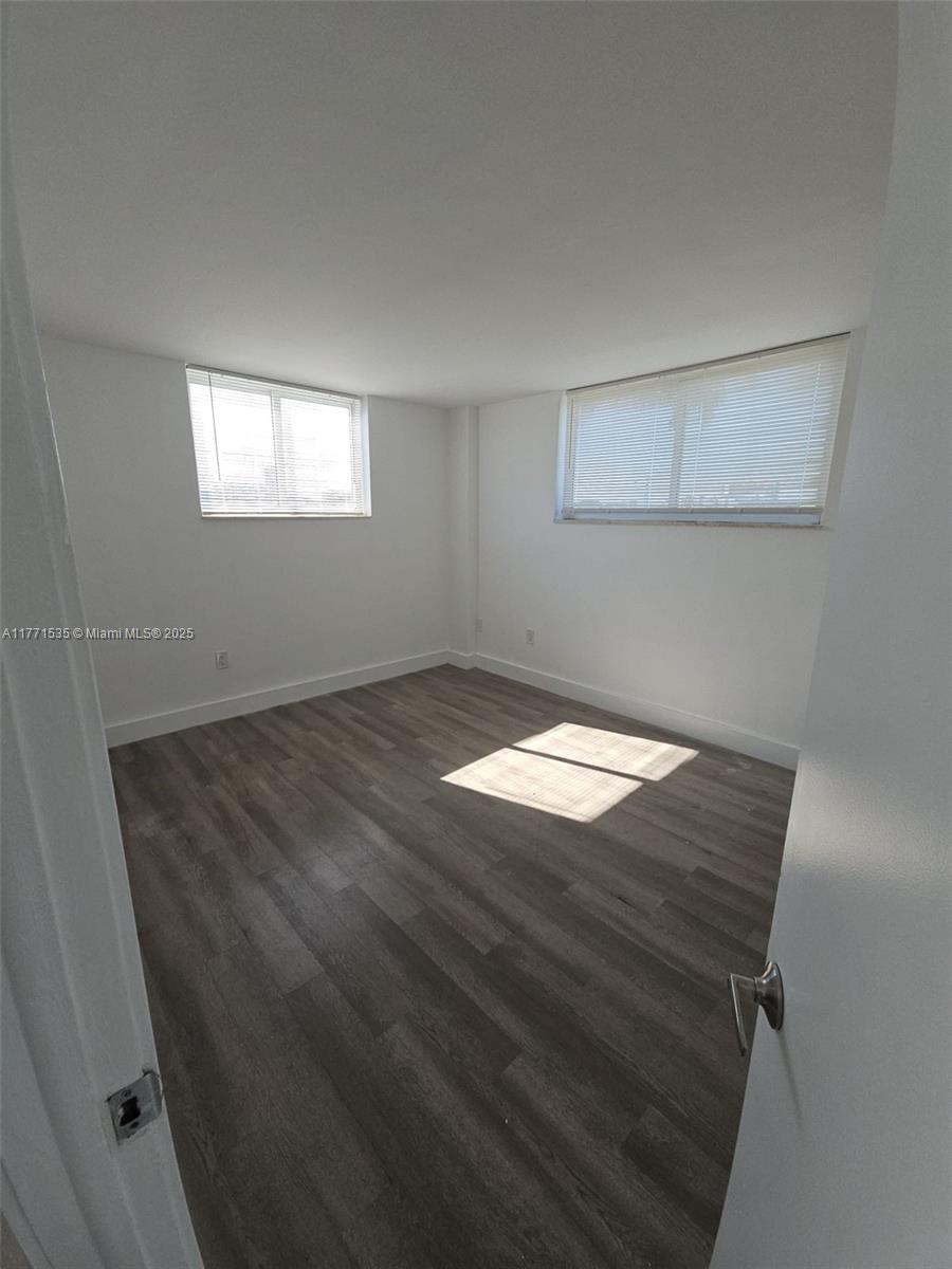 8101 Crespi Boulevard, Unit 304 Miami Beach, FL 33141 - Photo 9 of 25 an empty room with wooden floor cabinet and windows