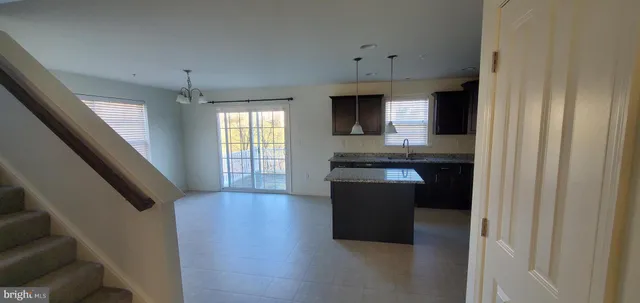 a kitchen with kitchen island granite countertop a sink and a stove top oven