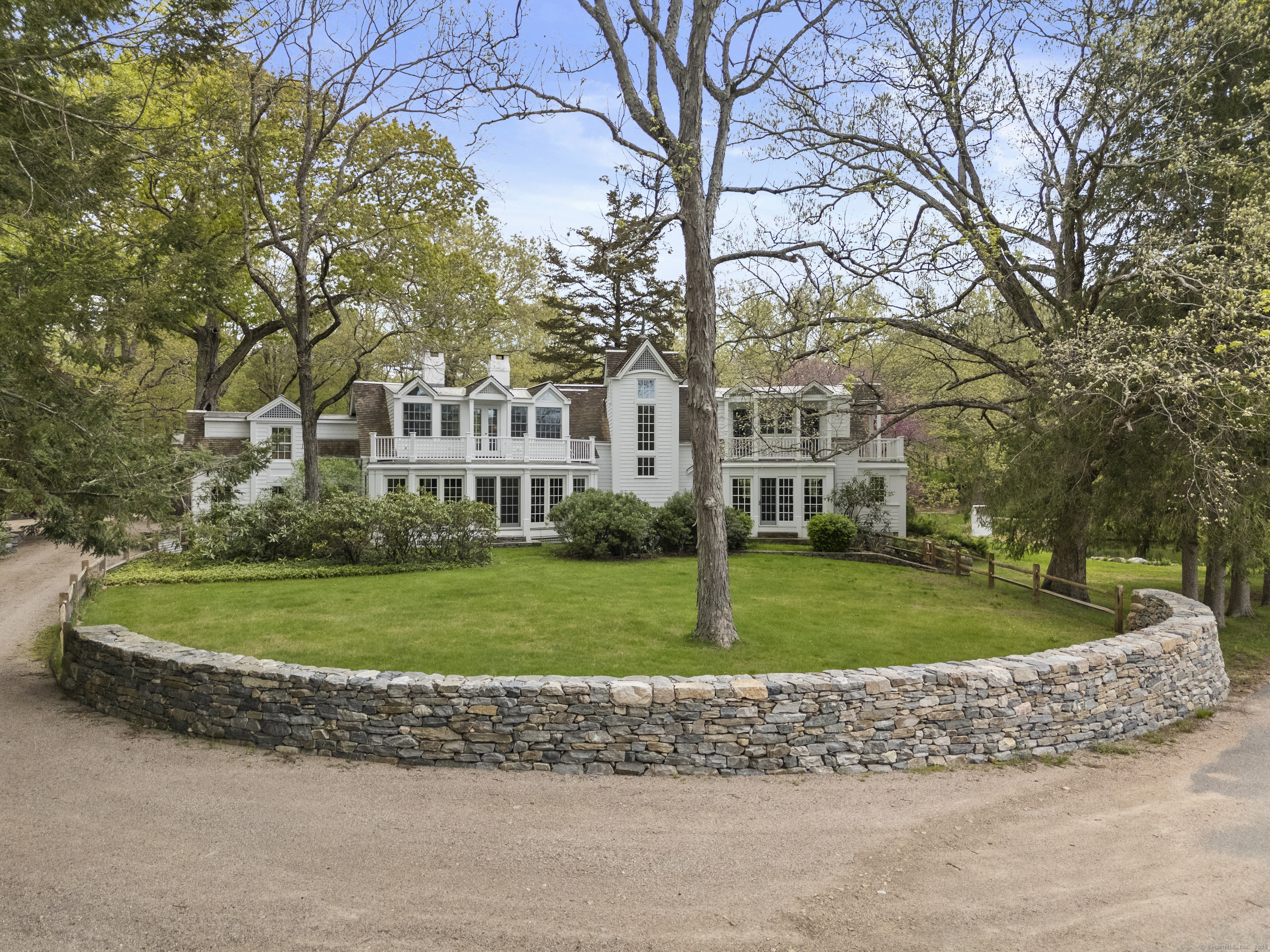 a view of a white house next to a yard with big trees