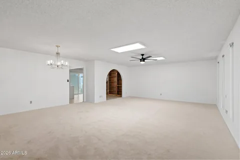 an empty room with chandelier fan and windows