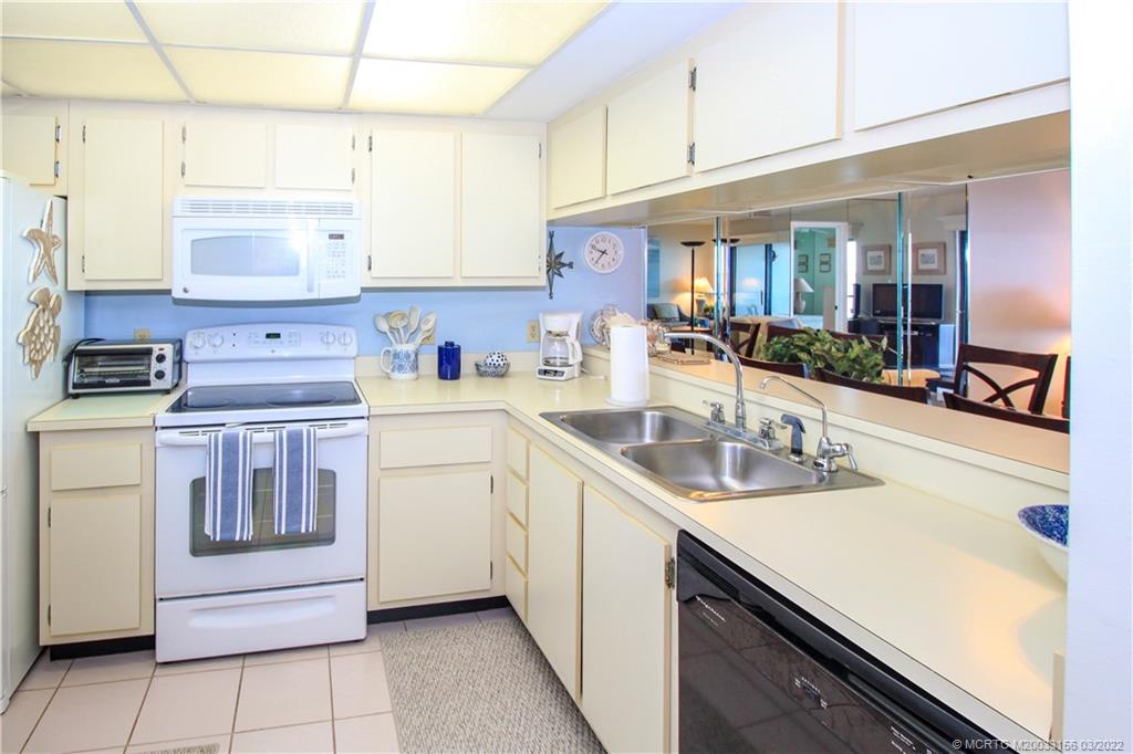 4440 Northeast Sandpebble Trace, Unit 403 Jensen Beach, FL 34957 - Photo 17 of 31 a kitchen with kitchen island a sink stove and cabinets