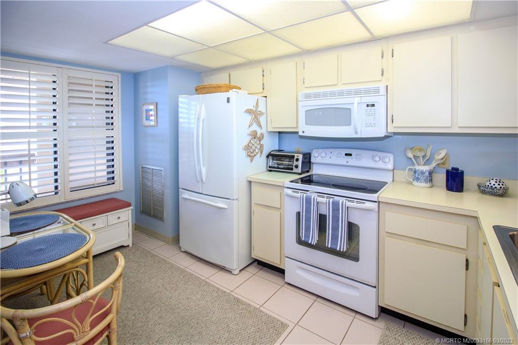 4440 Northeast Sandpebble Trace, Unit 403 Jensen Beach, FL 34957 - Photo 18 of 31 a kitchen that has a stove and a refrigerator