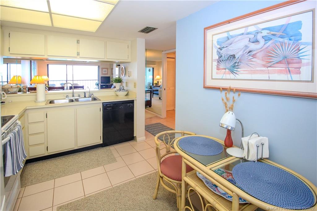 4440 Northeast Sandpebble Trace, Unit 403 Jensen Beach, FL 34957 - Photo 19 of 31 a kitchen with stainless steel appliances a sink a stove a table and chairs