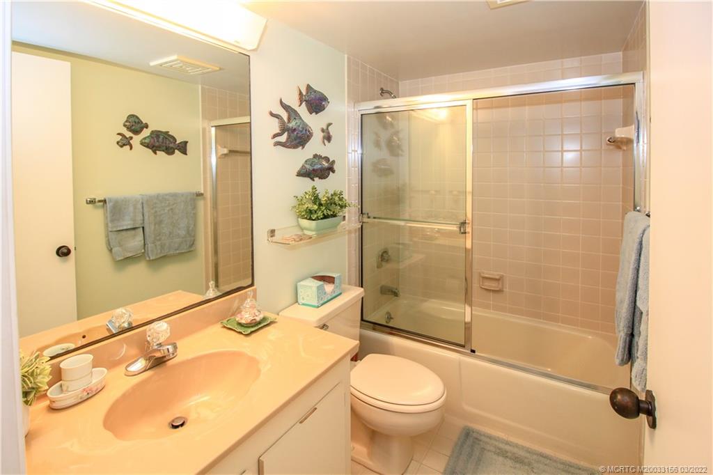 4440 Northeast Sandpebble Trace, Unit 403 Jensen Beach, FL 34957 - Photo 21 of 31 a bathroom with a shower sink vanity mirror and toilet