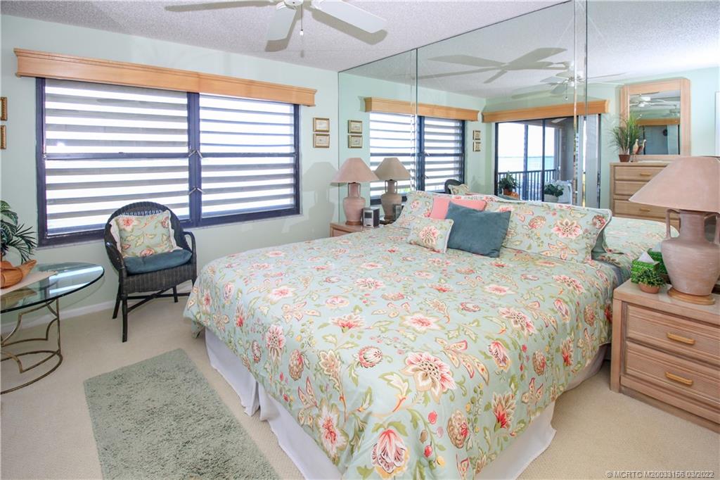 4440 Northeast Sandpebble Trace, Unit 403 Jensen Beach, FL 34957 - Photo 8 of 31 a bedroom with a bed and a chandelier