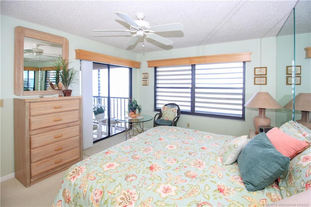 4440 Northeast Sandpebble Trace, Unit 403 Jensen Beach, FL 34957 - Photo 9 of 31 a bedroom with a bed a dresser and a large window