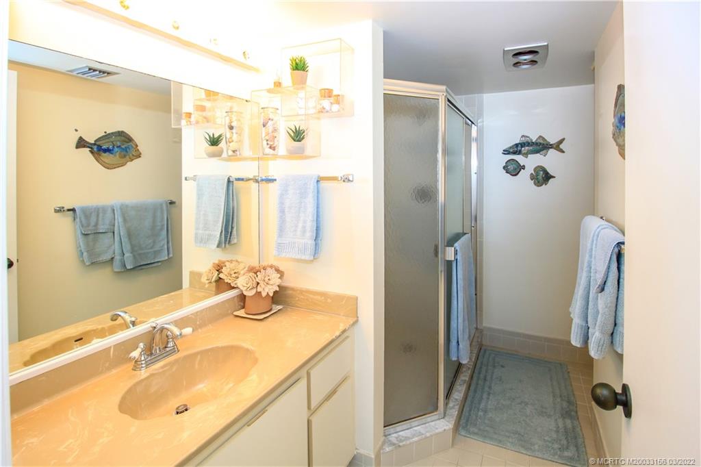 4440 Northeast Sandpebble Trace, Unit 403 Jensen Beach, FL 34957 - Photo 10 of 31 a bathroom with a granite countertop shower sink and mirror