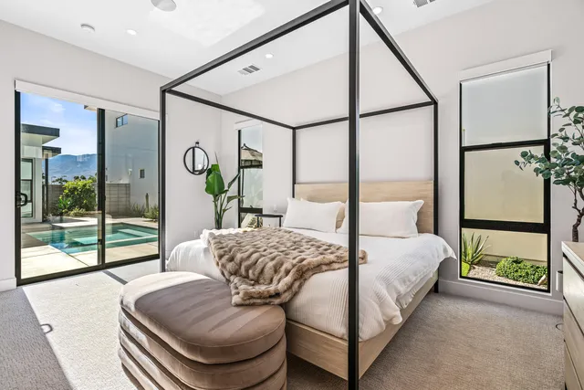 a bedroom with a bed and large window with balcony view