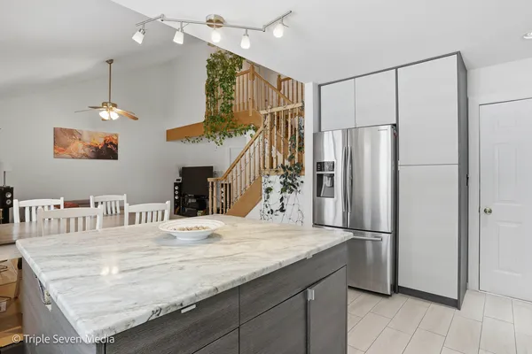 a kitchen with kitchen island a counter top space a refrigerator and a sink