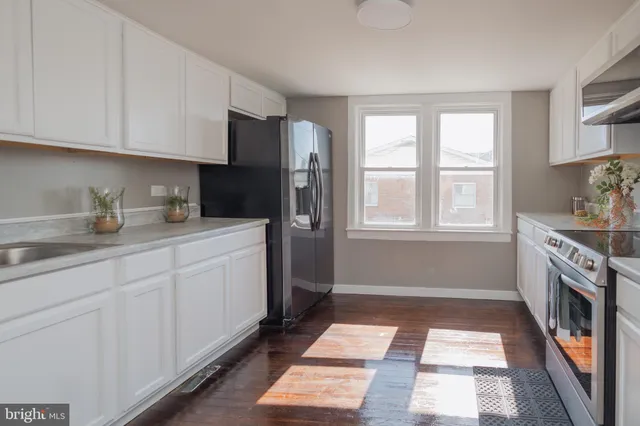a kitchen with stainless steel appliances granite countertop white cabinets and a refrigerator