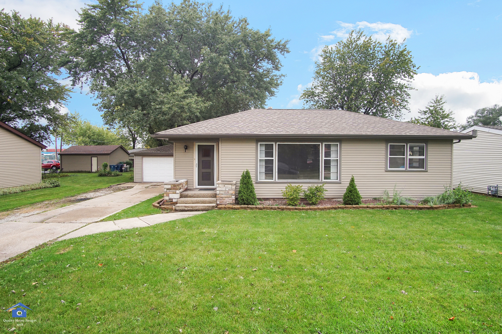 a front view of a house with a garden and trees