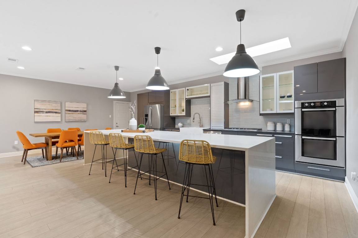 a open kitchen with stainless steel appliances granite countertop a stove a kitchen island a dining table and chairs with wooden floor