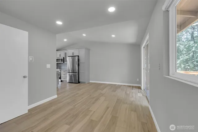 a view of empty room with wooden floor and window
