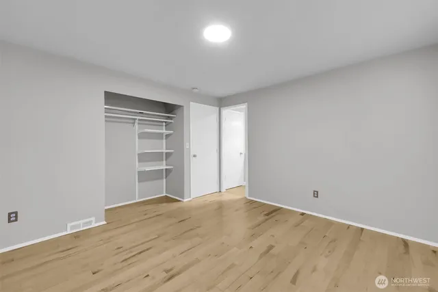 a view of an empty room with a window and wooden floor