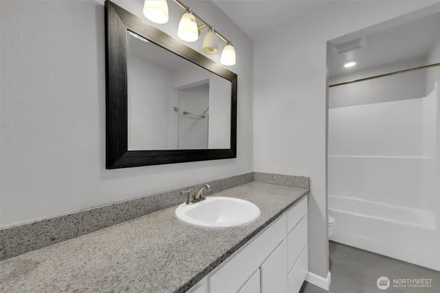 a bathroom with a granite countertop sink and a mirror