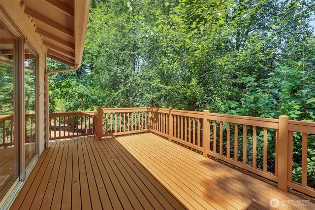 a balcony with wooden floor and trees in the back