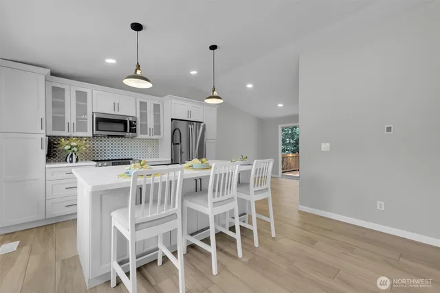 a kitchen with stainless steel appliances a dining table chairs refrigerator and microwave