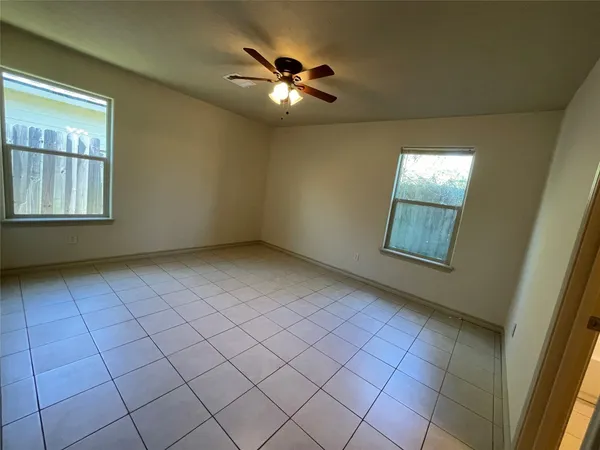an empty room with windows and fan
