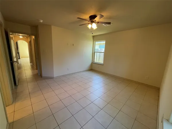 en empty room with windows and chandelier fan