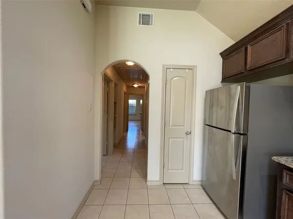 a view of a refrigerator in kitchen and an empty room