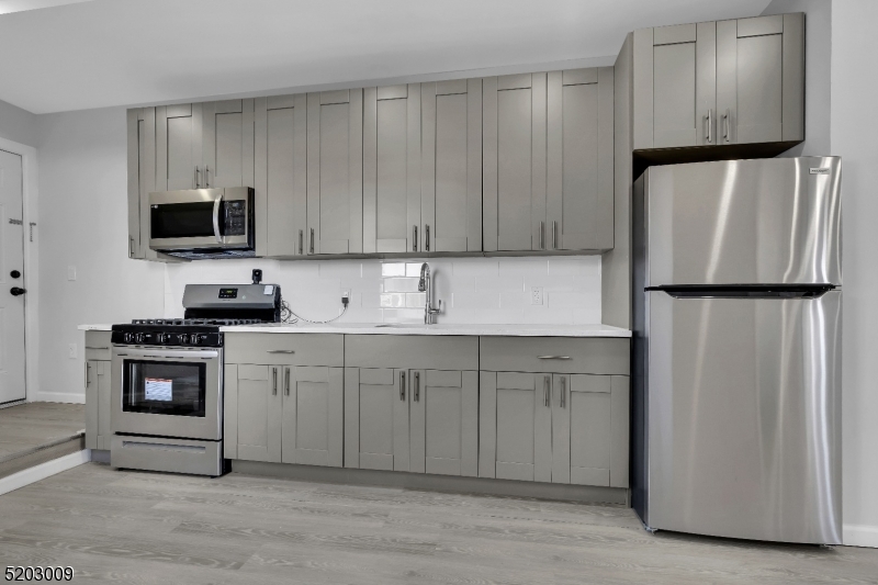 167 Smith Street, Unit 1L Elizabeth, NJ 07201 - Photo 3 of 8 a kitchen with white cabinets and stainless steel appliances